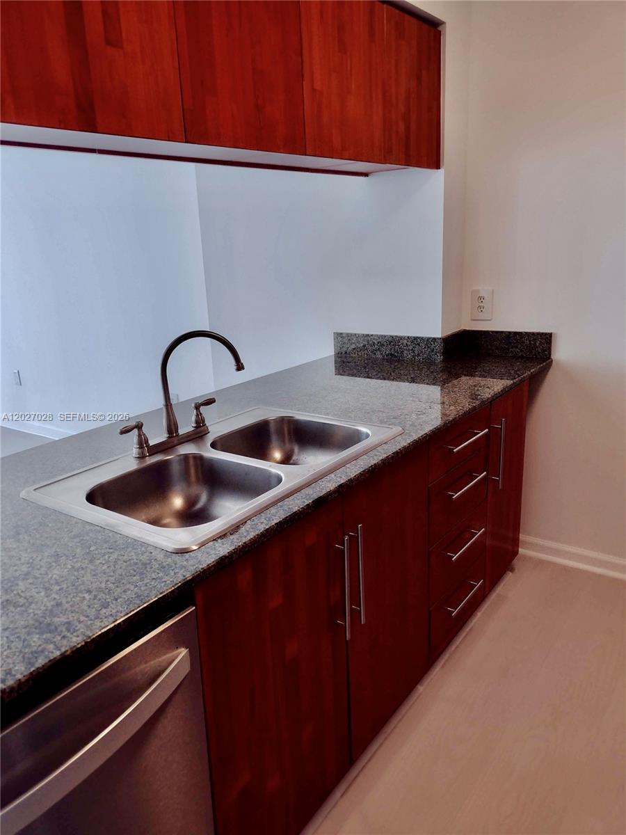 A kitchen features dark wood cabinets, a granite countertop, and a double stainless steel sink — 1200 Brickell Bay Dr # 2005, Miami FL 33131, MIAMI, FL