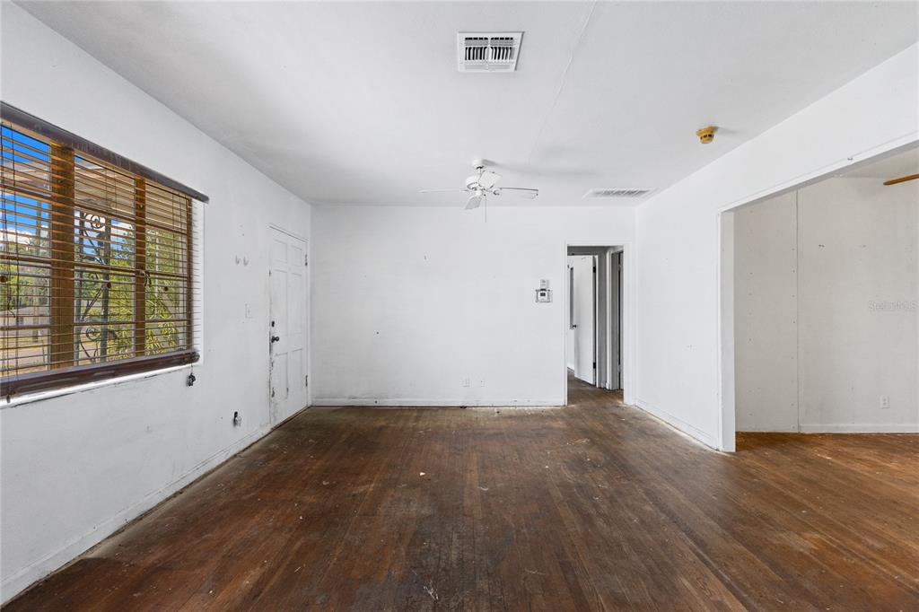 An empty room with white walls, a ceiling fan, and dark wood flooring — 2025 17TH AVENUE W, BRADENTON, FL