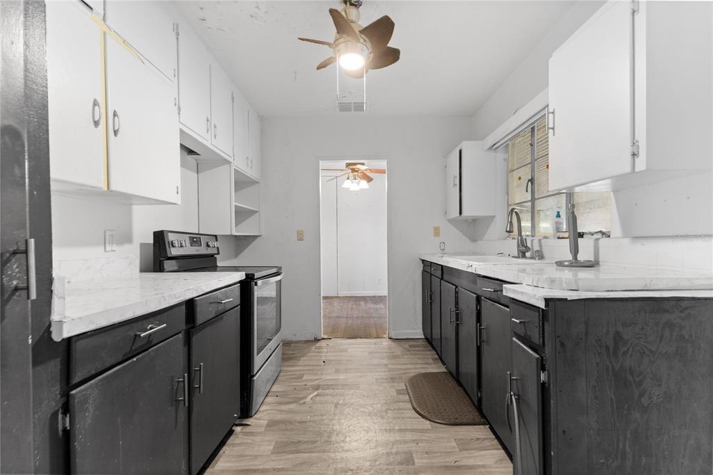 A galley kitchen features dark lower cabinets, white upper cabinets, and light-colored countertops — 2025 17TH AVENUE W, BRADENTON, FL