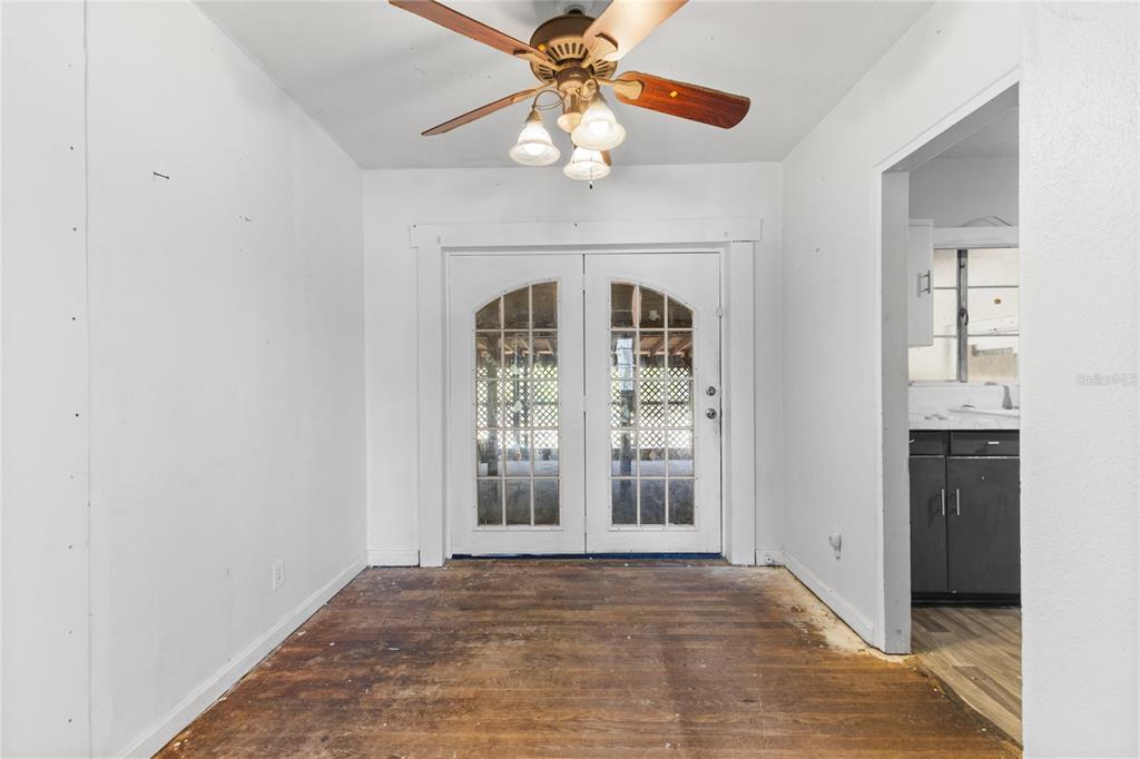 An empty room with hardwood floors, a ceiling fan, and white French doors — 2025 17TH AVENUE W, BRADENTON, FL