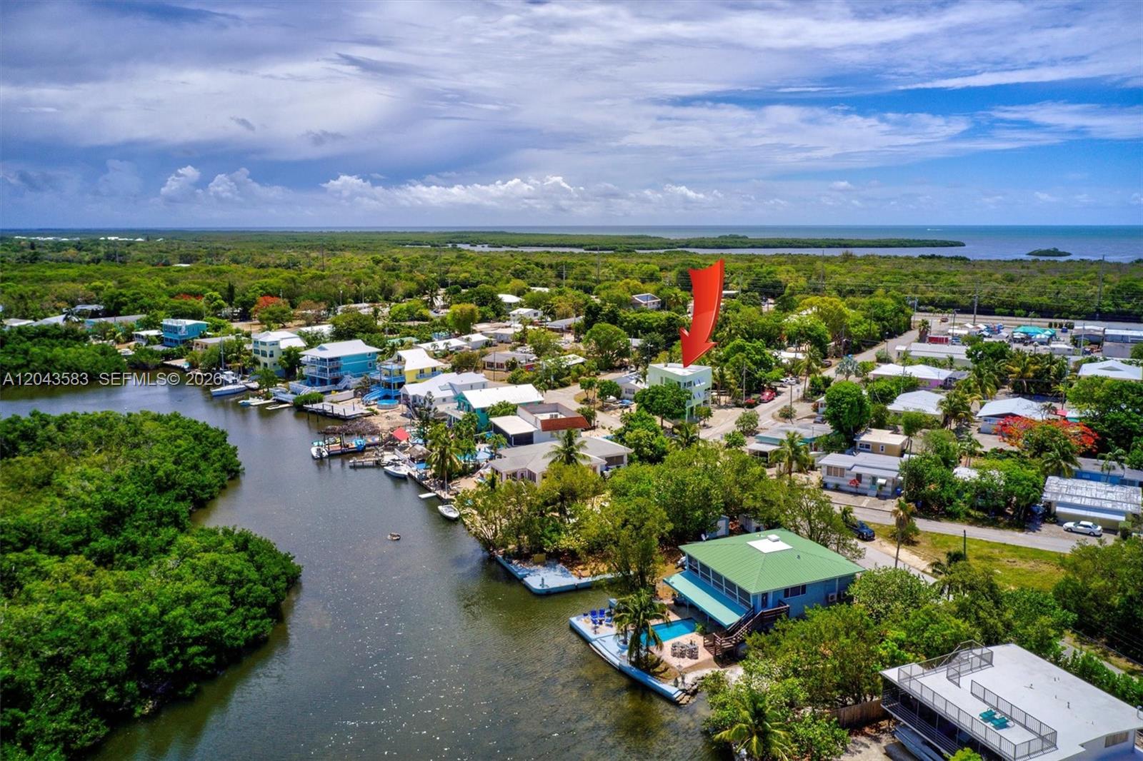 An aerial view shows a coastal neighborhood with houses, lush vegetation, and a waterway — 19 Park Drive, Key Largo FL 33037, KEY LARGO, FL