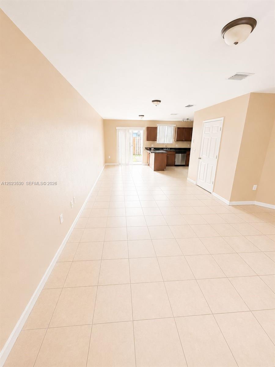 An open-concept living and kitchen area features light-colored tile flooring and beige walls — 1827 NW 142nd Ln, Opa-Locka FL 33054, OPA-LOCKA, FL