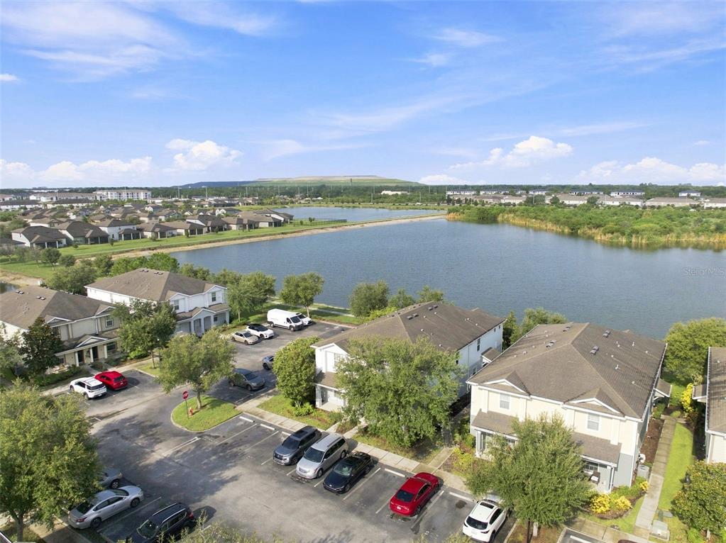 An aerial view shows multi-story residential buildings near a large lake under a blue sky — 4755 SOMERSET HILL LANE, RIVERVIEW, FL