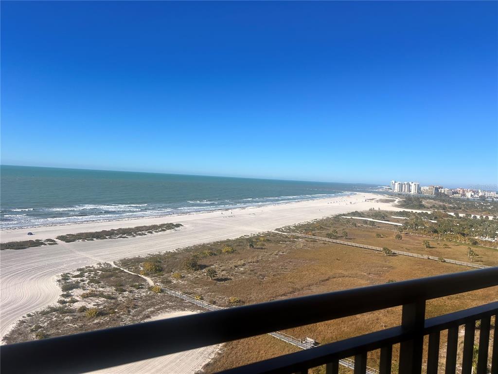 An elevated view of a sandy beach, ocean, and coastal vegetation from a balcony — 1270 GULF BOULEVARD UNIT 1403, CLEARWATER, FL