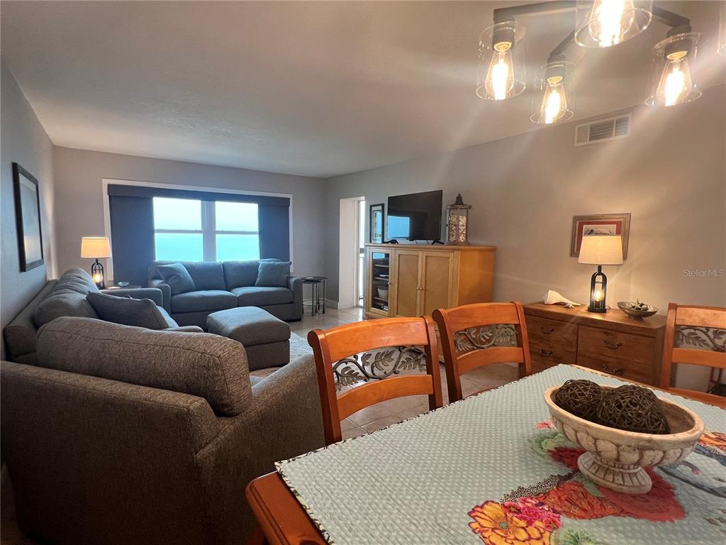 A living and dining area features a gray sectional sofa, wooden furniture, and a chandelier — 1270 GULF BOULEVARD UNIT 1403, CLEARWATER, FL