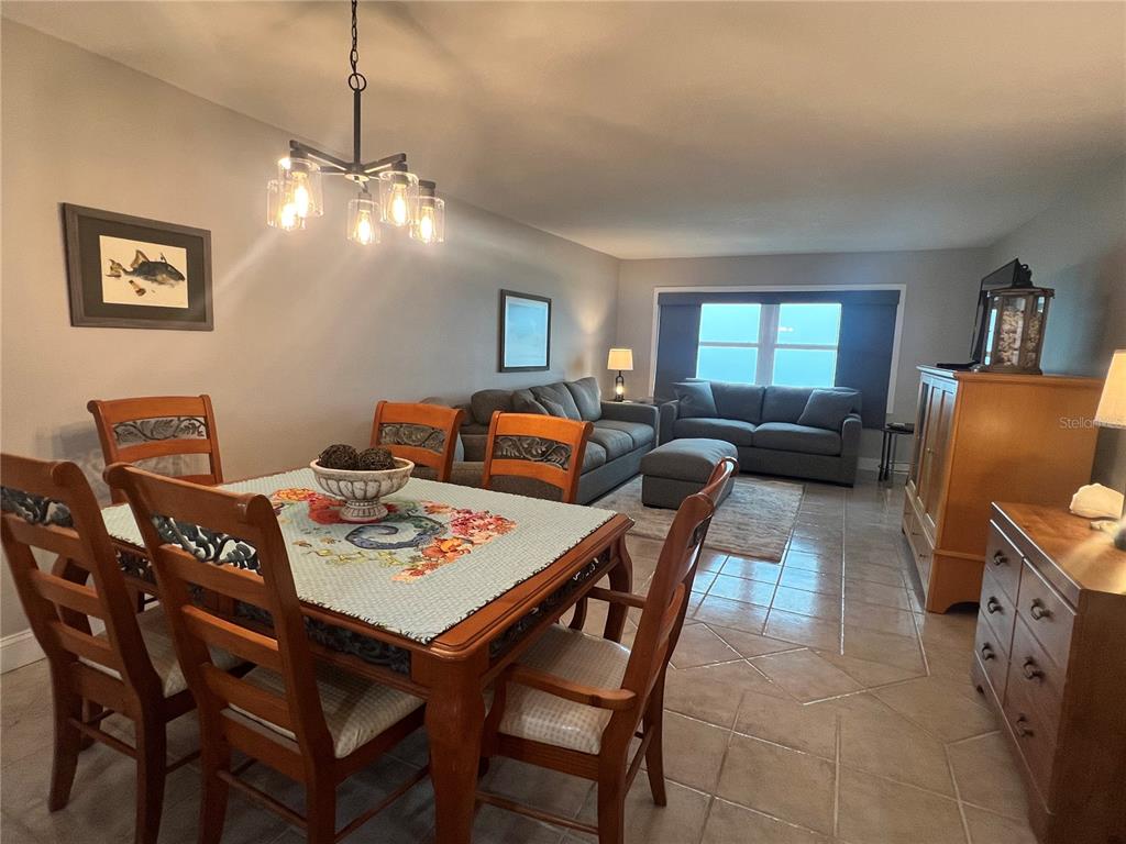A dining area with a wooden table and chairs opens into a living room — 1270 GULF BOULEVARD UNIT 1403, CLEARWATER, FL