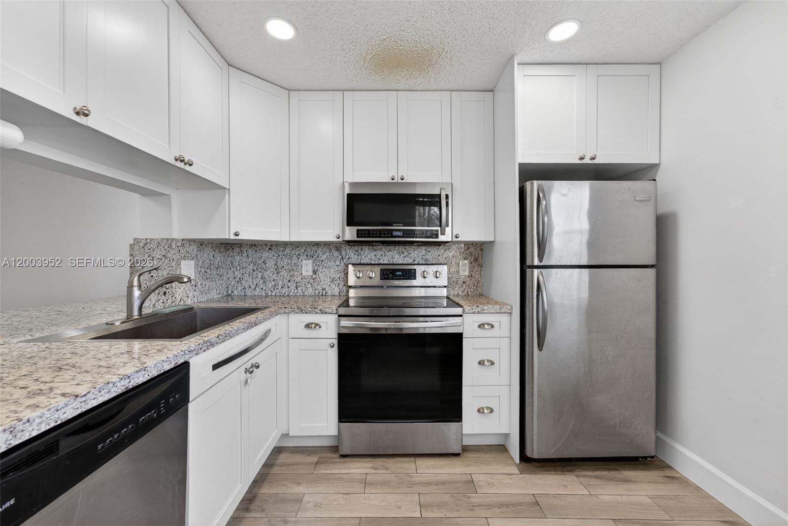 A kitchen features white cabinets, stainless steel appliances, and granite countertops — 889 Hamilton Dr # 889D, Homestead FL 33034, HOMESTEAD, FL