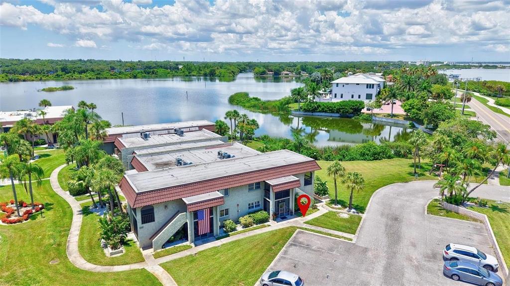 An aerial view shows a multi-story apartment building with a parking lot and lake — 1001 S BAYSHORE BOULEVARD UNIT 101, SAFETY HARBOR, FL