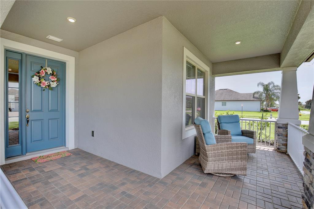 A covered front porch features a blue door, brick pavers, and two wicker chairs — 3266 KAYAK WAY, ORLANDO, FL