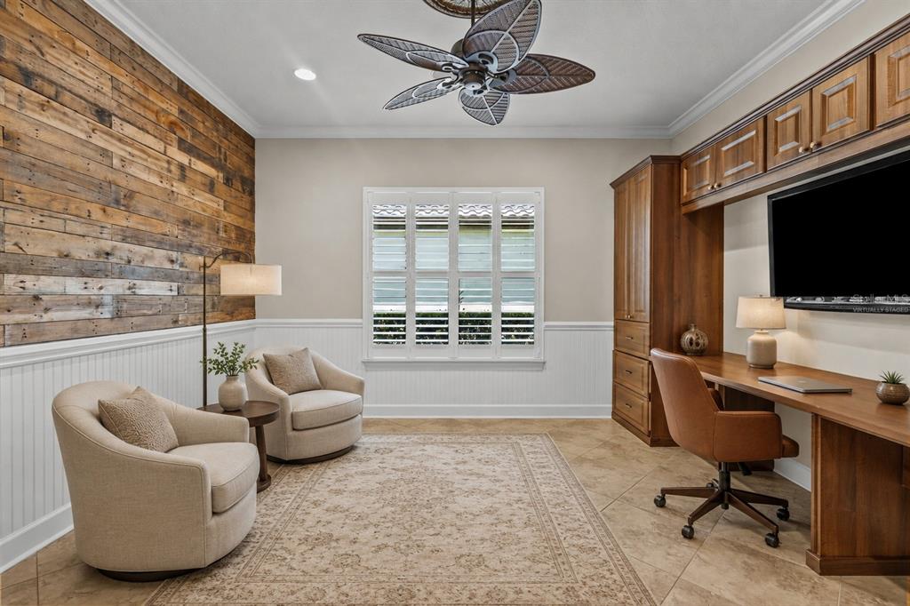 A home office features a wood-paneled wall, built-in cabinetry, a desk, and two armchairs — 9913 WICKER PARK PLACE, PALMETTO, FL