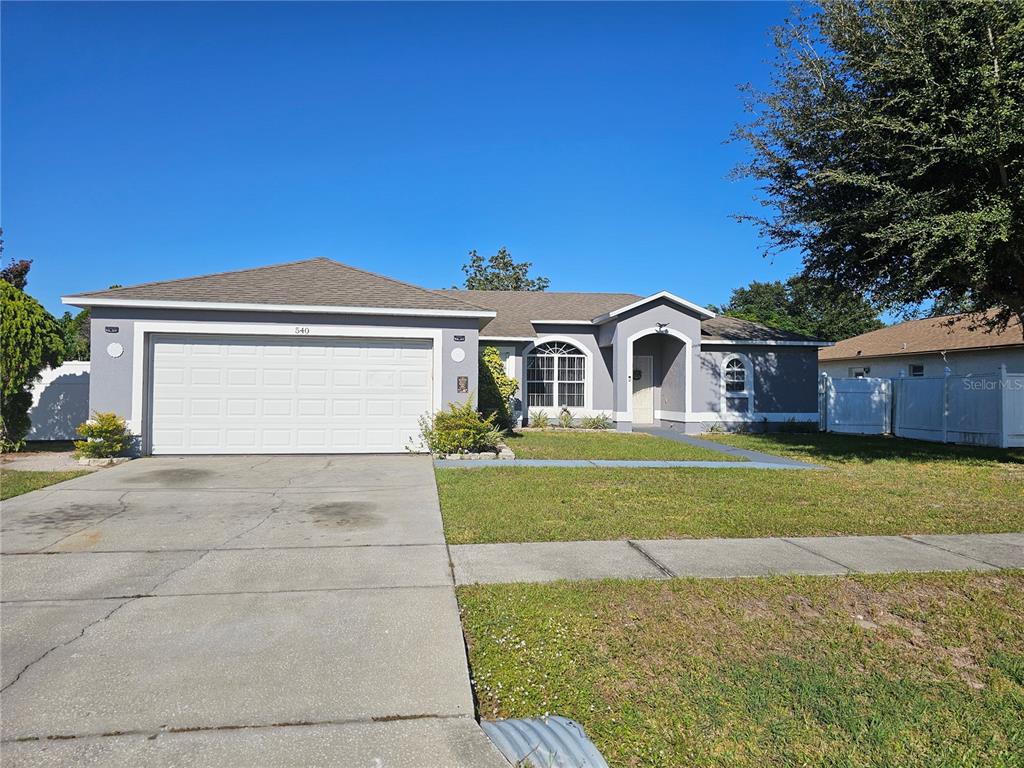 A single-story house with a gray exterior, a two-car garage, and a concrete driveway — 540 OAK BRANCH CIRCLE, KISSIMMEE, FL