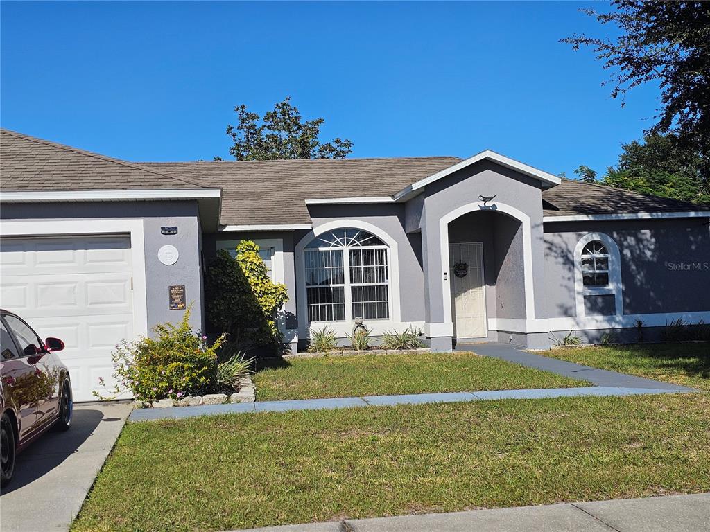 A gray single-story house with a white garage door, arched window, and covered entryway — 540 OAK BRANCH CIRCLE, KISSIMMEE, FL