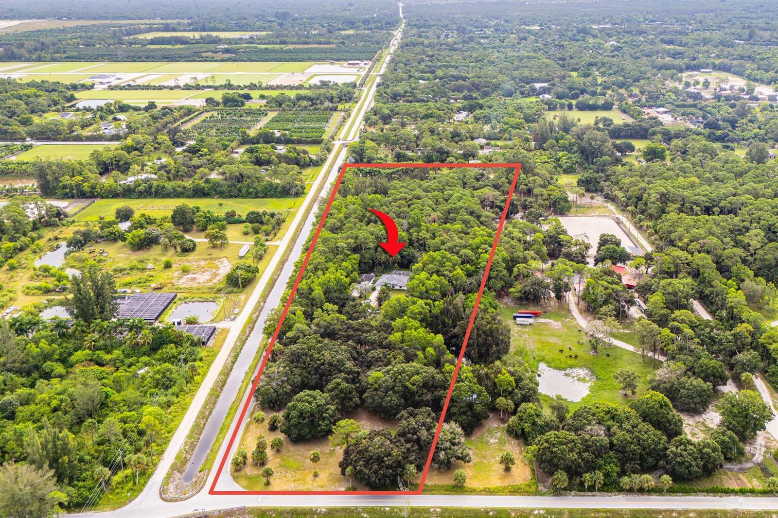 An aerial view shows a house nestled within a large, wooded lot outlined in red — 15884 North Road, FL 33470, FL