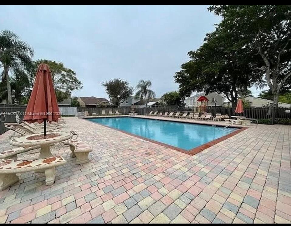 A rectangular swimming pool is surrounded by a brick paver deck with tables and chairs — 15813 W Waterside Circle # 206, Sunrise FL 33326, SUNRISE, FL