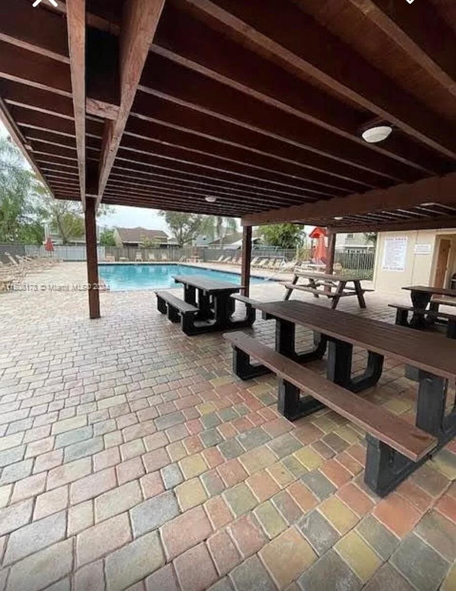 A covered patio with picnic tables overlooks a swimming pool on a paved deck — 15813 W Waterside Circle # 206, Sunrise FL 33326, SUNRISE, FL