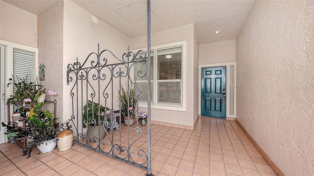 An entryway features a decorative metal gate, potted plants, and a teal front door — 5420 EAGLES POINT CIRCLE UNIT 402, SARASOTA, FL