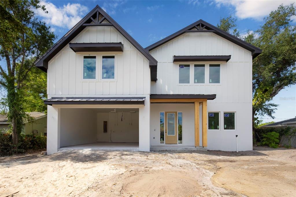 A two-story modern farmhouse with white vertical siding, a metal roof, and an open garage — 2114 FLOYD STREET, SARASOTA, FL
