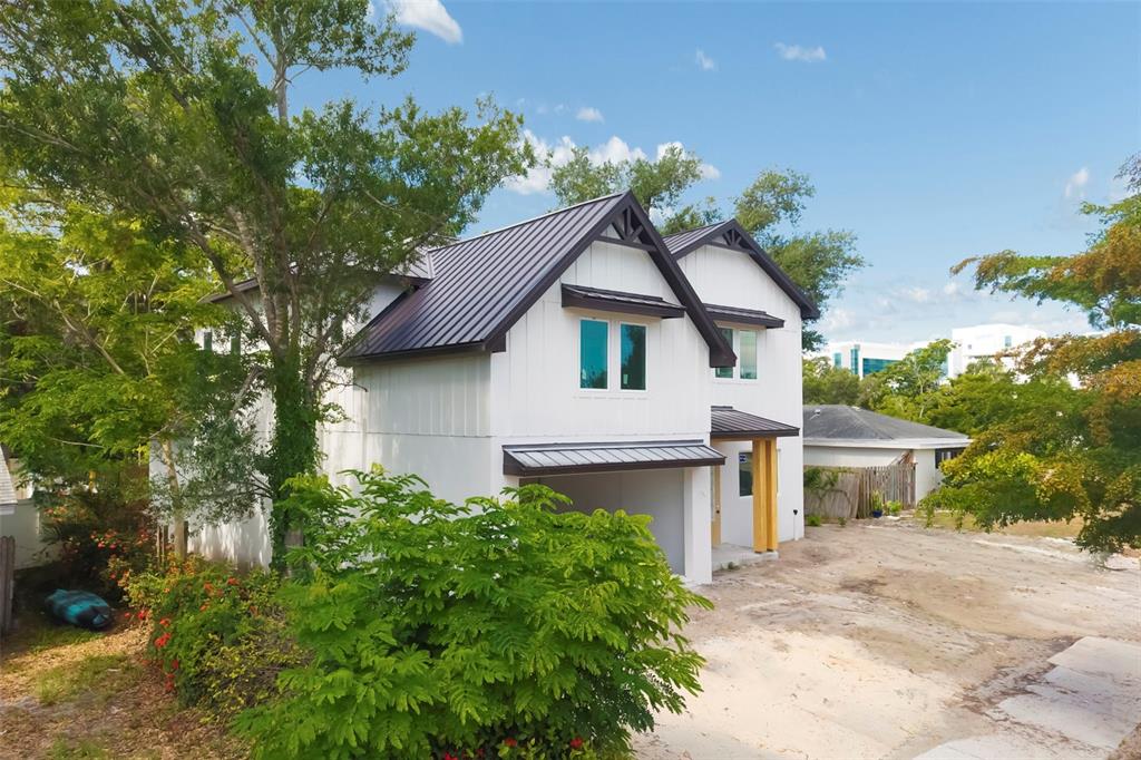 A two-story white house with a dark metal roof and a front-facing garage — 2114 FLOYD STREET, SARASOTA, FL