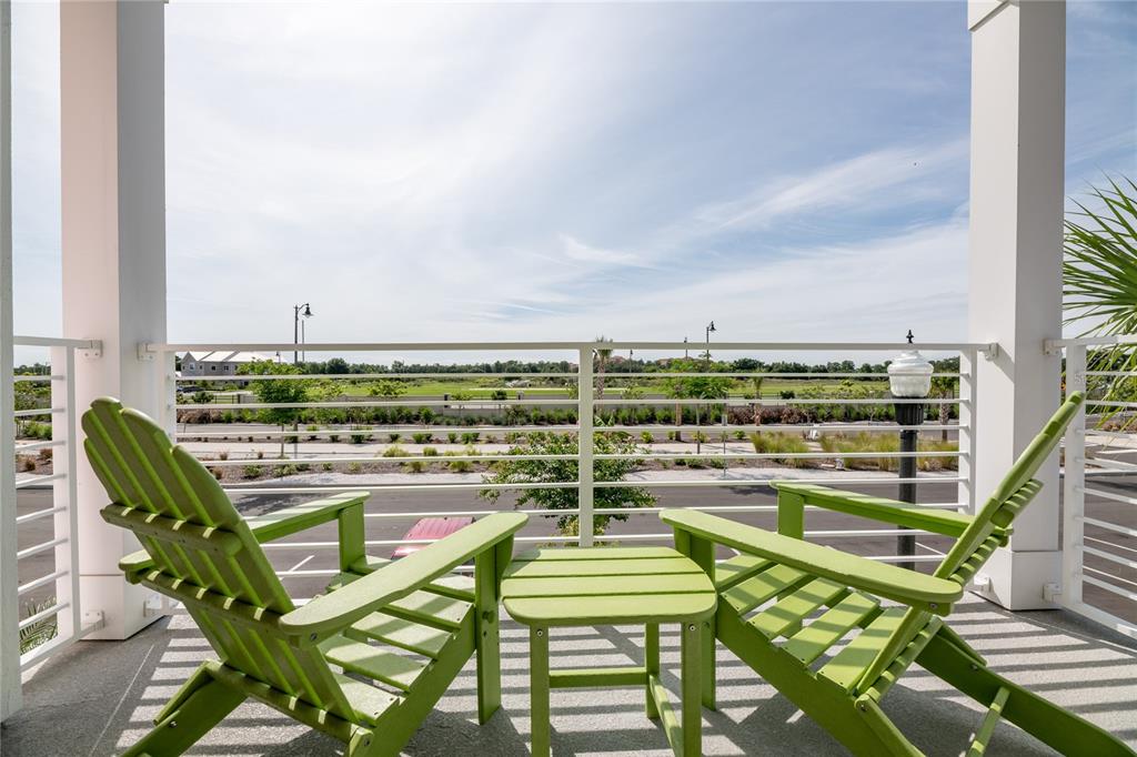 Two green Adirondack chairs and a small table sit on a balcony overlooking a street — 2956 SALTED RIM ROAD, KISSIMMEE, FL