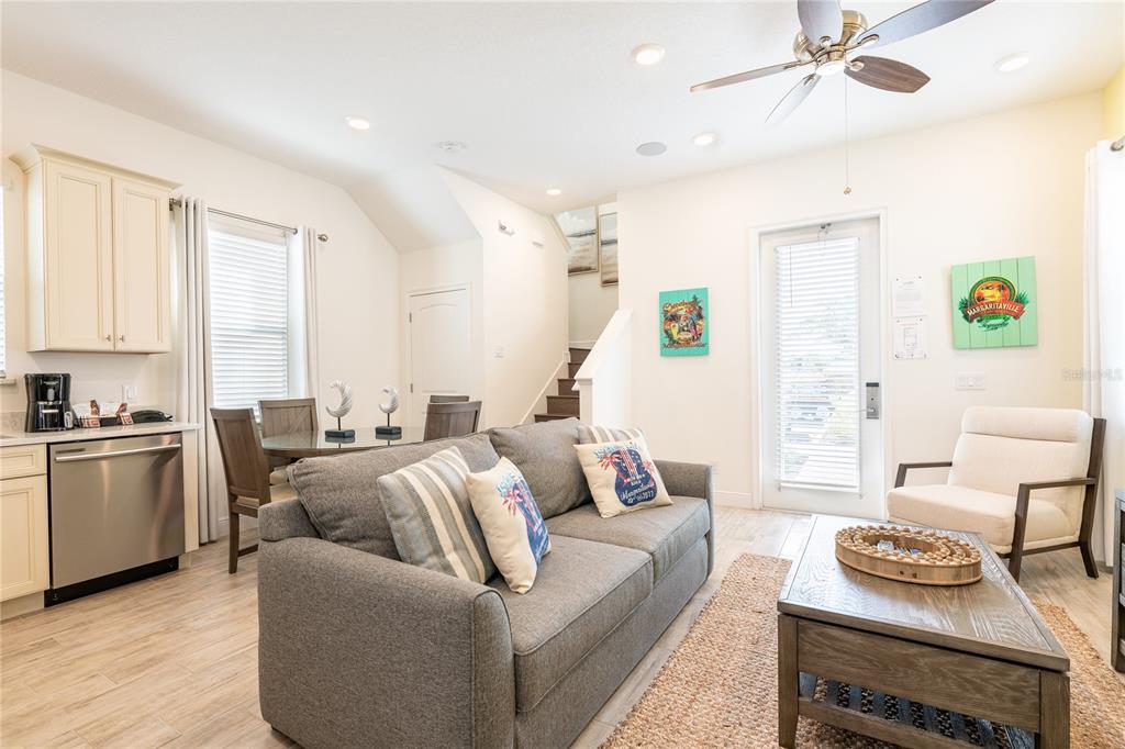 A living room with a gray sofa, coffee table, kitchen area, and stairs — 2956 SALTED RIM ROAD, KISSIMMEE, FL