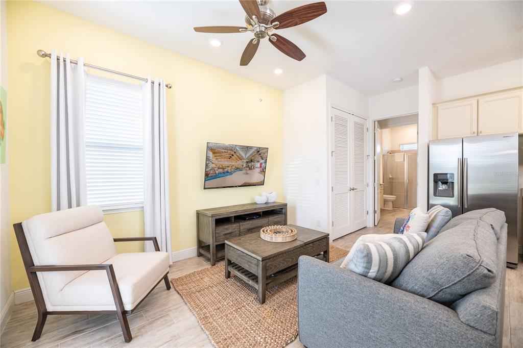A living room features a yellow wall, gray sofa, armchair, and a television — 2956 SALTED RIM ROAD, KISSIMMEE, FL