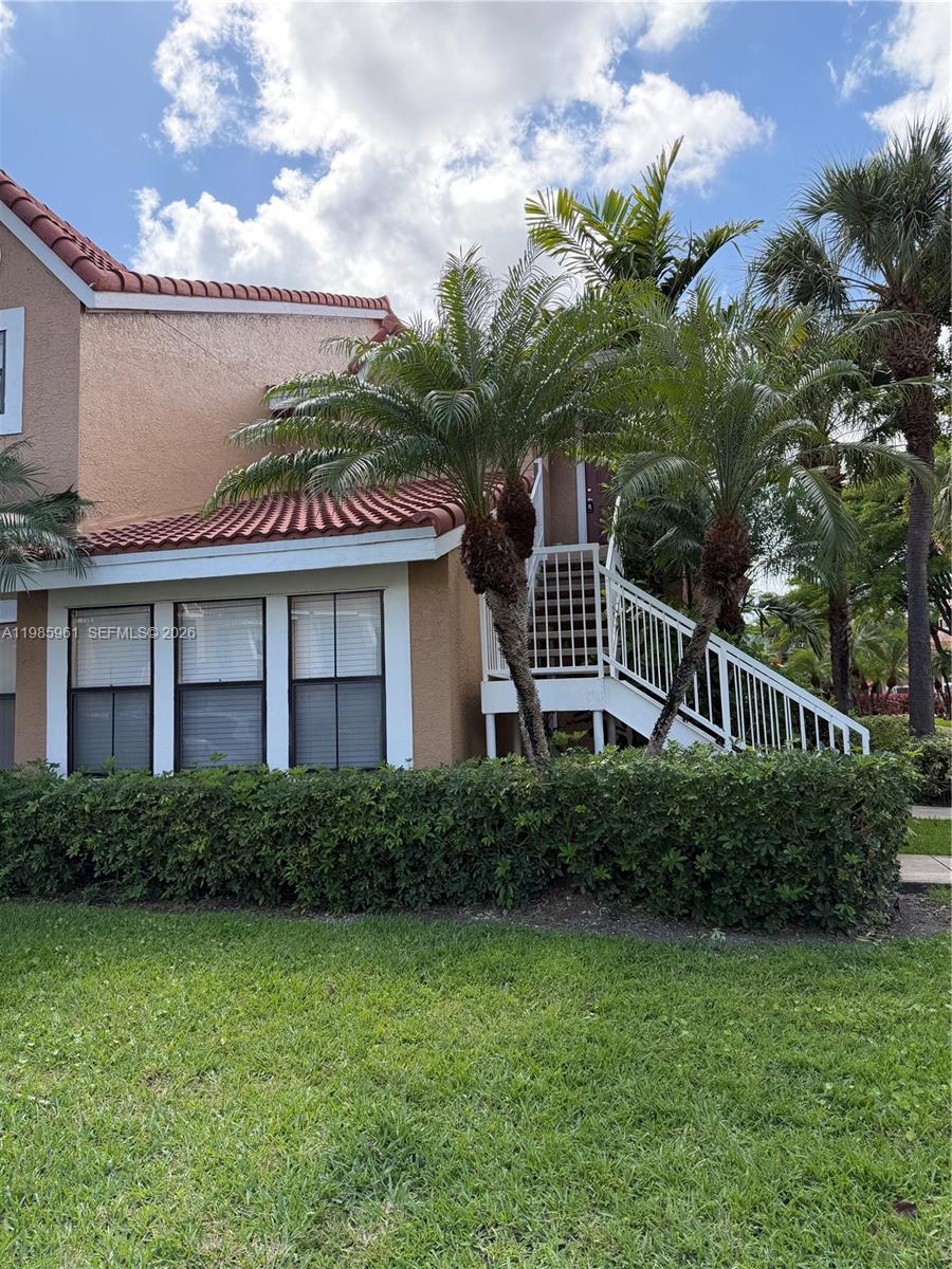 A two-story tan building features a white staircase, palm trees, and a green hedge — 10500 SW 155th Ct # 1026, Miami FL 33196, MIAMI, FL