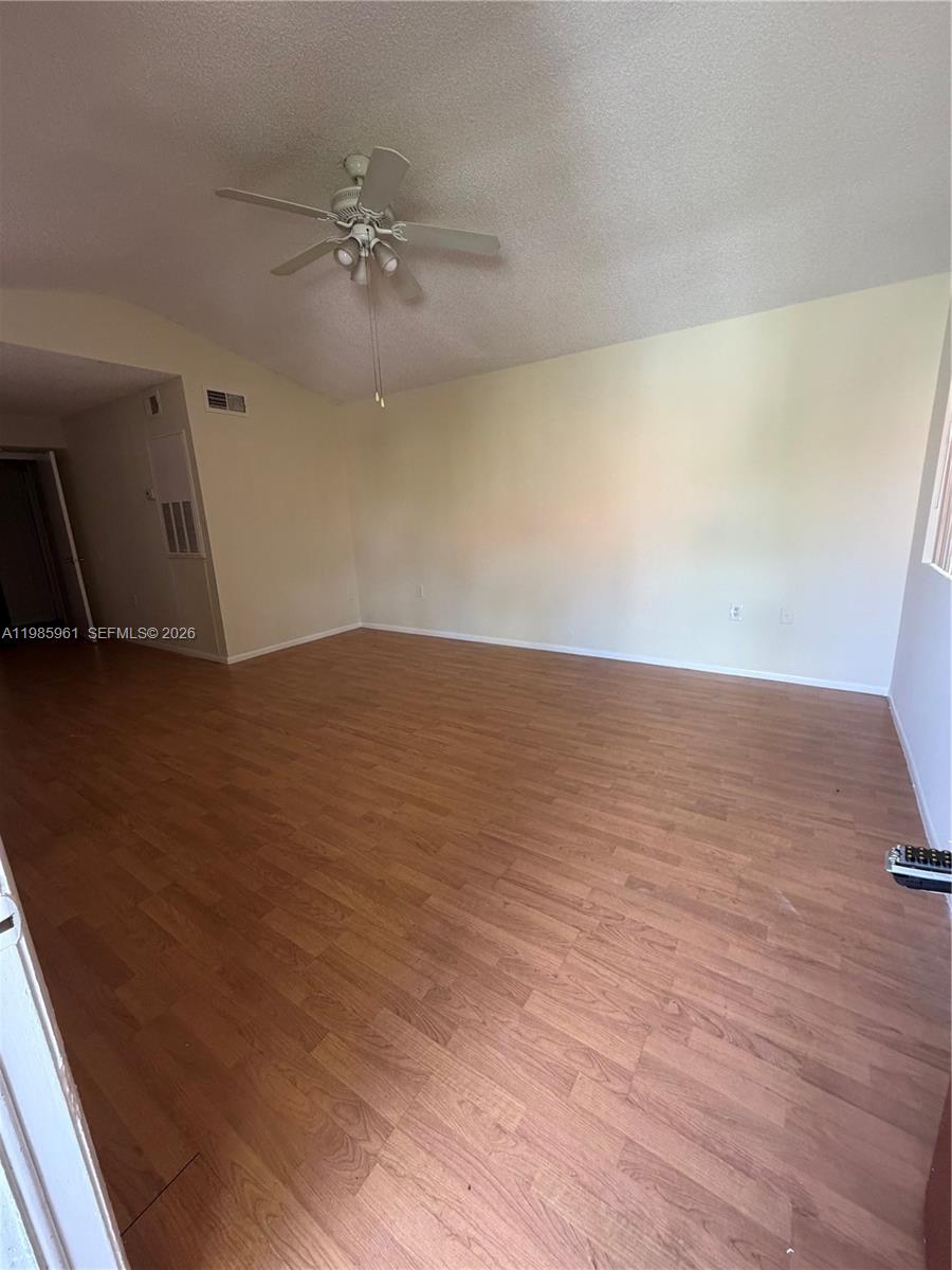 An empty room features light-colored walls, a ceiling fan, and wood-look laminate flooring — 10500 SW 155th Ct # 1026, Miami FL 33196, MIAMI, FL