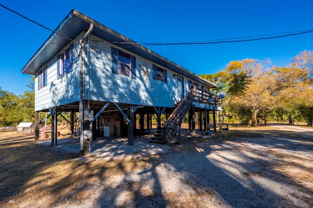 An elevated light blue house with a wooden staircase and a concrete ground-level patio — 2207 SW BLOSSOM AVENUE, ARCADIA, FL