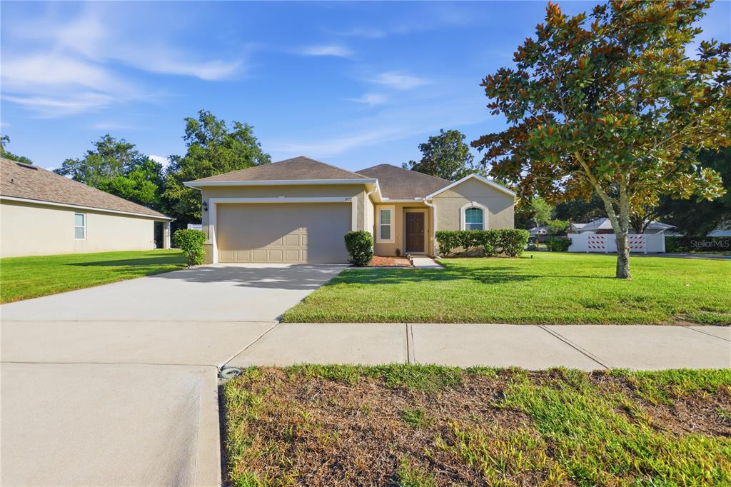 A single-story house with a beige exterior, a two-car garage, and a front lawn — 802 GRAND PARK COURT, DELAND, FL