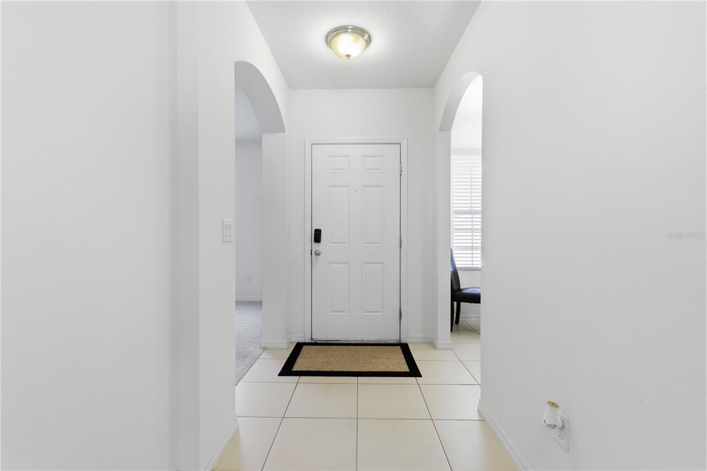 A bright entryway features white walls, tiled flooring, and arched doorways leading to other rooms — 802 GRAND PARK COURT, DELAND, FL