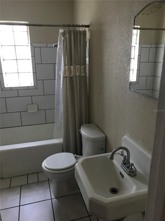 A bathroom features a white pedestal sink, a toilet, and a shower-tub combo with tile — 118 RIGGINS STREET, LAKELAND, FL