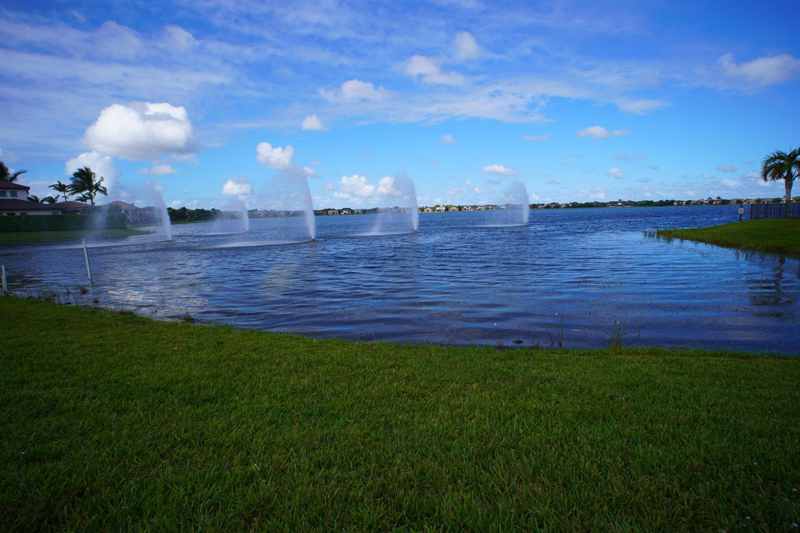 A large lake features several water fountains with houses visible in the background — 8965 Watercrest Circle E, Parkland FL 33076, PARKLAND, FL