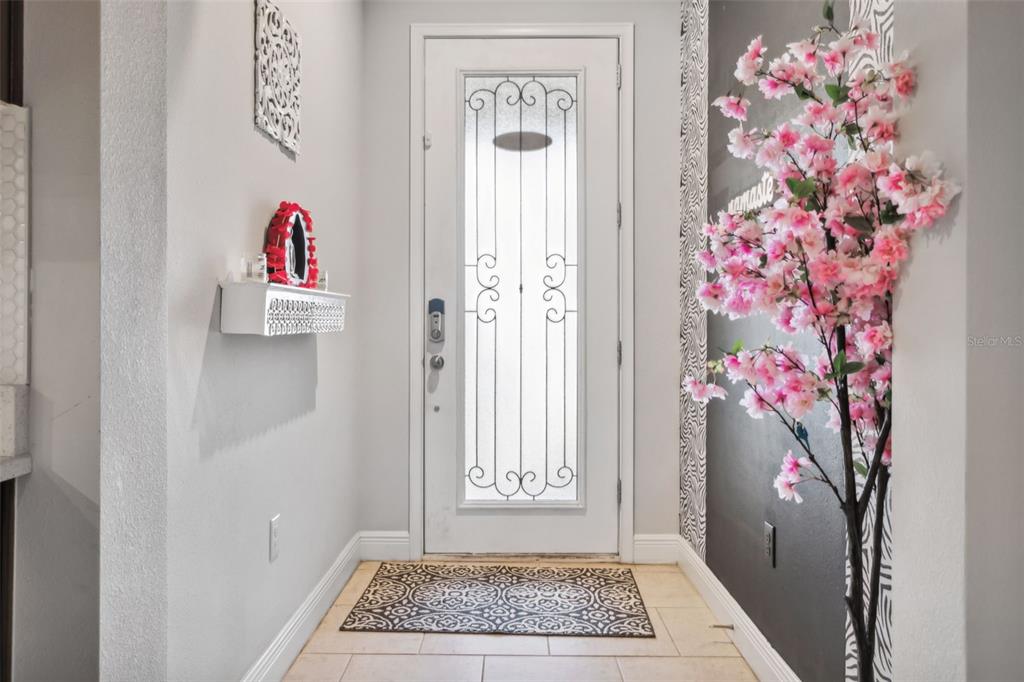 An entryway features a white front door with decorative glass, tile flooring, and a cherry blossom tree — 5950 GRAND SONATA AVENUE, LUTZ, FL