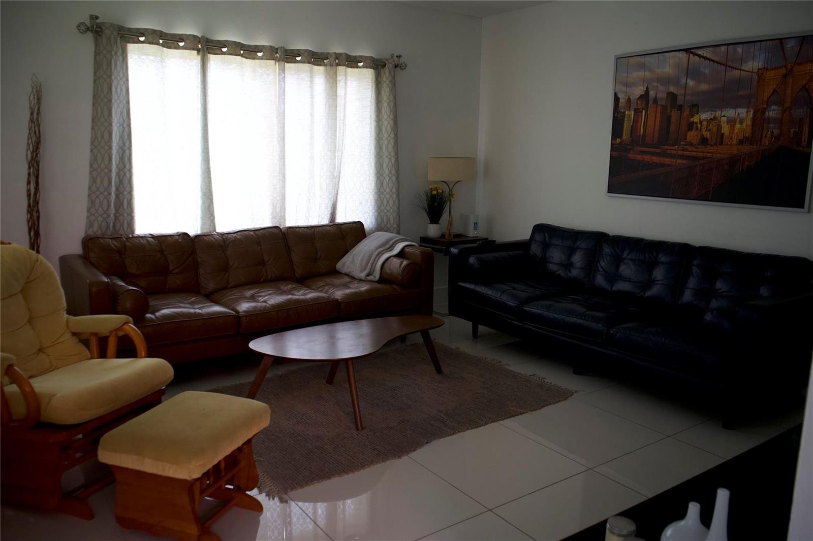 A living room features a brown leather sofa, a black leather sofa, and a yellow chair — 11150 Peachtree Drive, Miami FL 33161, MIAMI, FL