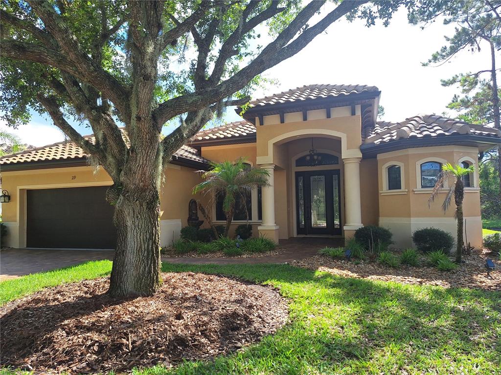 A single-story stucco house with a tile roof, a two-car garage, and a large tree — 29 N LAKEWALK DRIVE, PALM COAST, FL