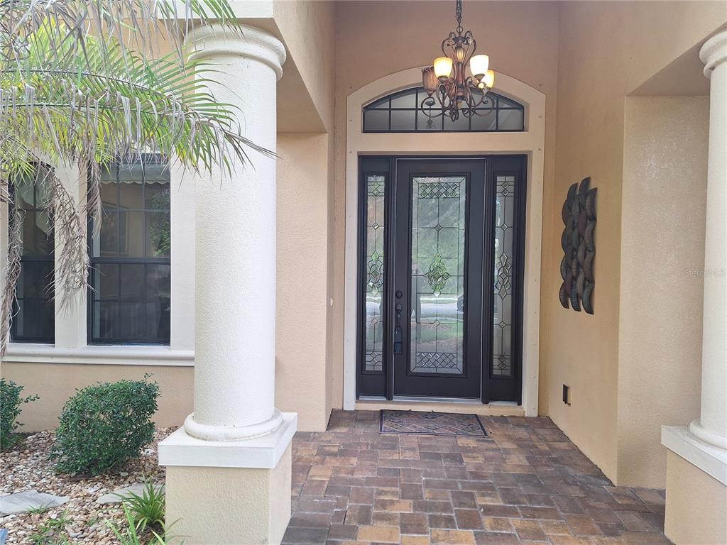 A front entryway features a dark glass-paneled door, a chandelier, and stone paver flooring — 29 N LAKEWALK DRIVE, PALM COAST, FL