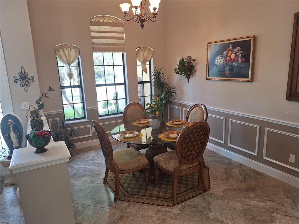 A dining room features a glass-topped table, four chairs, tile flooring, and wainscoting — 29 N LAKEWALK DRIVE, PALM COAST, FL