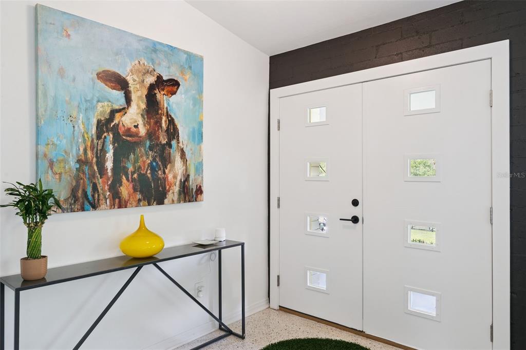 An entryway features a white double door, a cow painting, and a black console table — 10426 LAKESHORE DRIVE, CLERMONT, FL