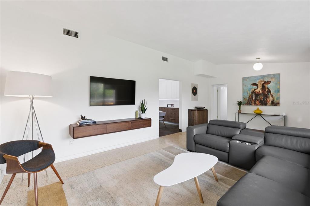 A living room features a wall-mounted television, a floating wooden console, and a grey sectional — 10426 LAKESHORE DRIVE, CLERMONT, FL