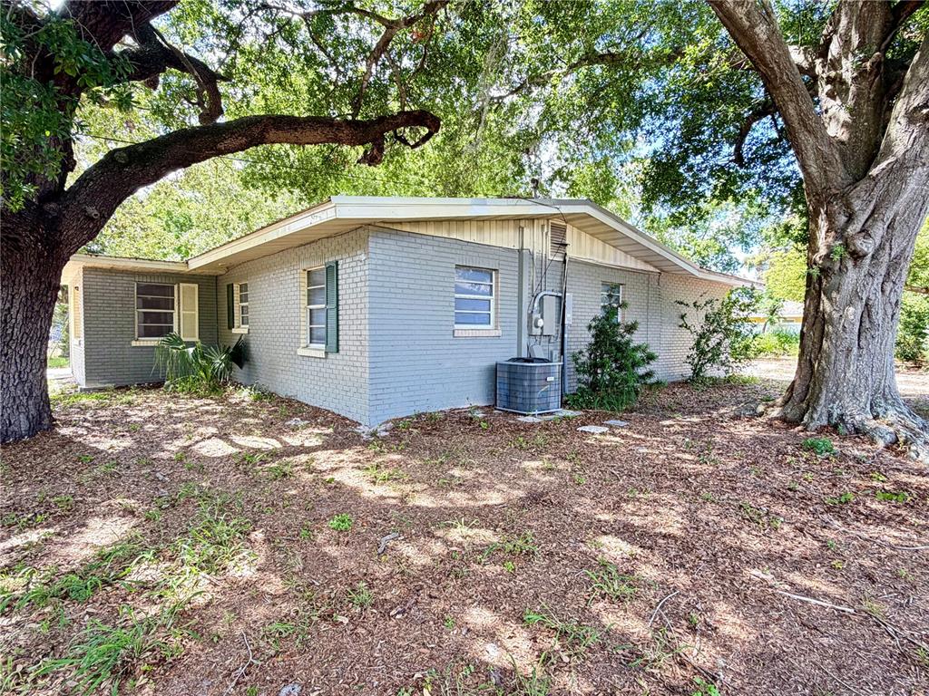 A gray brick house with a gabled roof sits under large trees — 1405 AVENUE H SW, WINTER HAVEN, FL