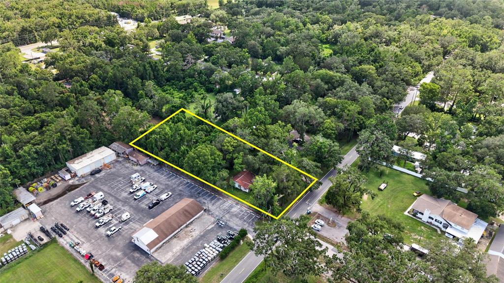 An aerial view shows a rectangular wooded lot with a small house next to parking — 19370 FORT DADE AVENUE, BROOKSVILLE, FL