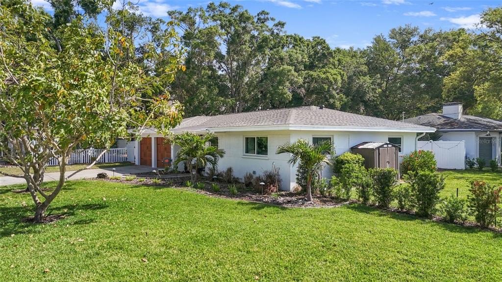 A white single-story house with a lawn, palm trees, and a detached storage shed — 101 N MERCURY AVENUE, CLEARWATER, FL