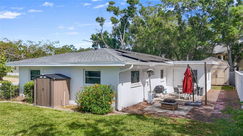 The exterior of a white house features a patio, solar panels, and two storage sheds — 101 N MERCURY AVENUE, CLEARWATER, FL