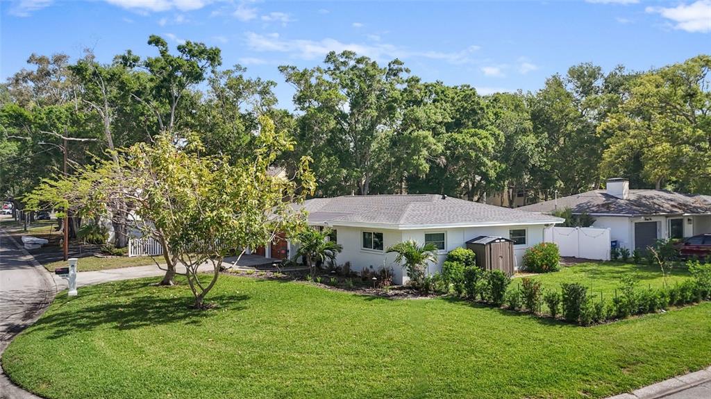 A white single-story house with a gray roof sits on a corner lot with trees — 101 N MERCURY AVENUE, CLEARWATER, FL