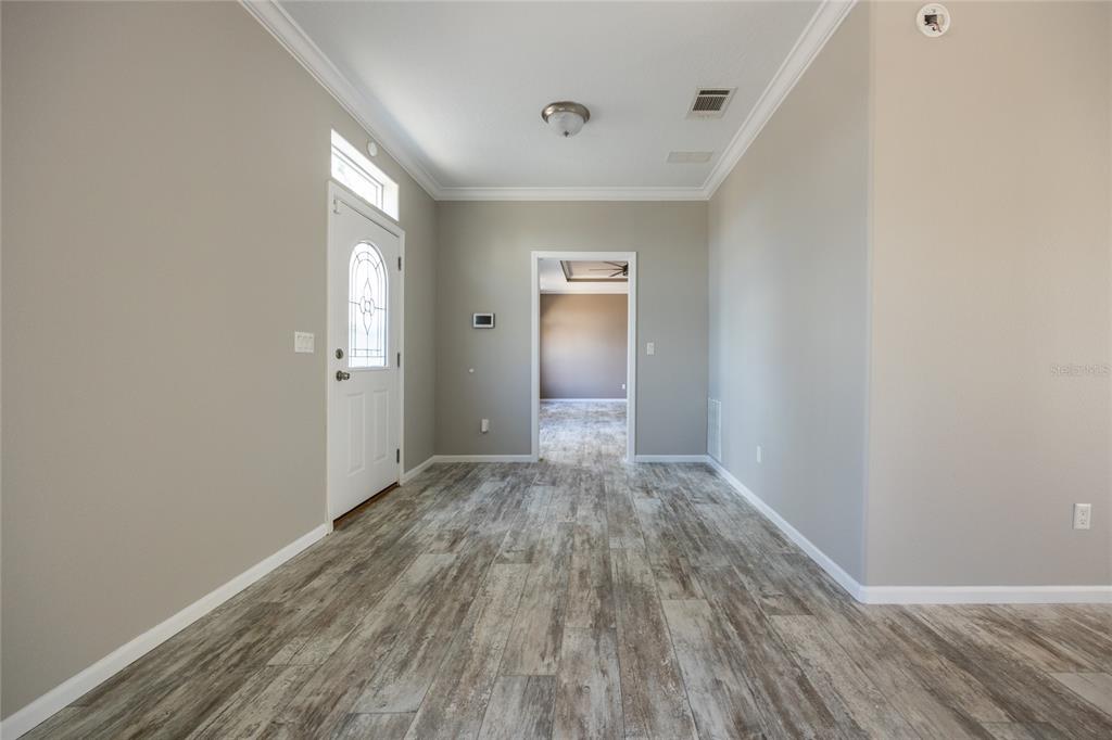 An entryway with light gray walls, wood-look tile flooring, and a white front door — 6671 SW 128TH LANE, LAKE BUTLER, FL
