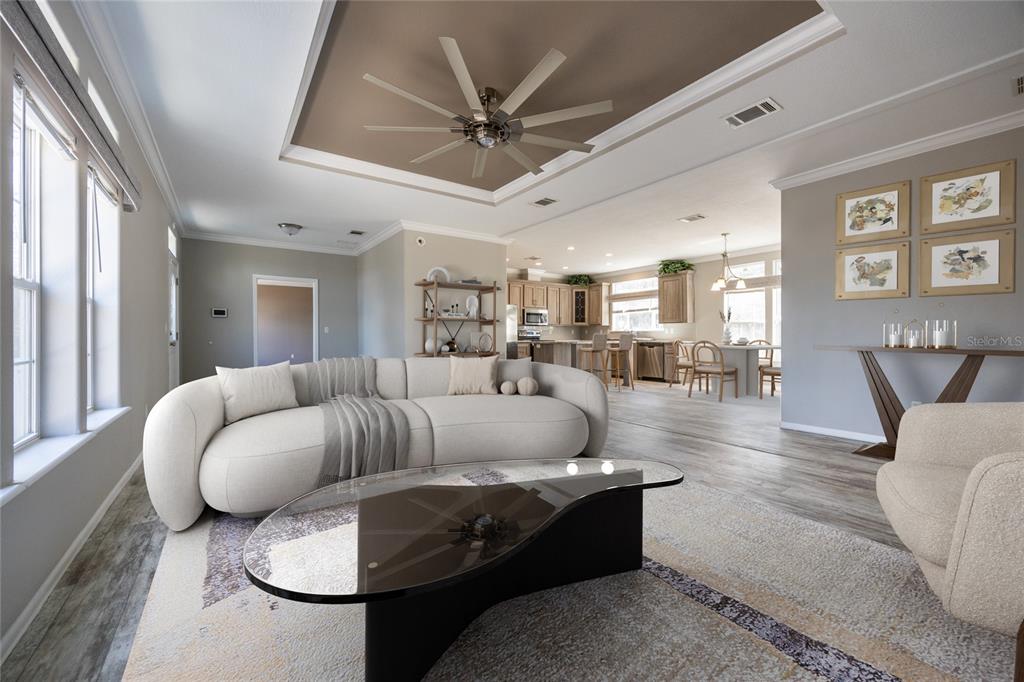 A living room with a curved sofa, glass coffee table, and open kitchen in the background — 6671 SW 128TH LANE, LAKE BUTLER, FL
