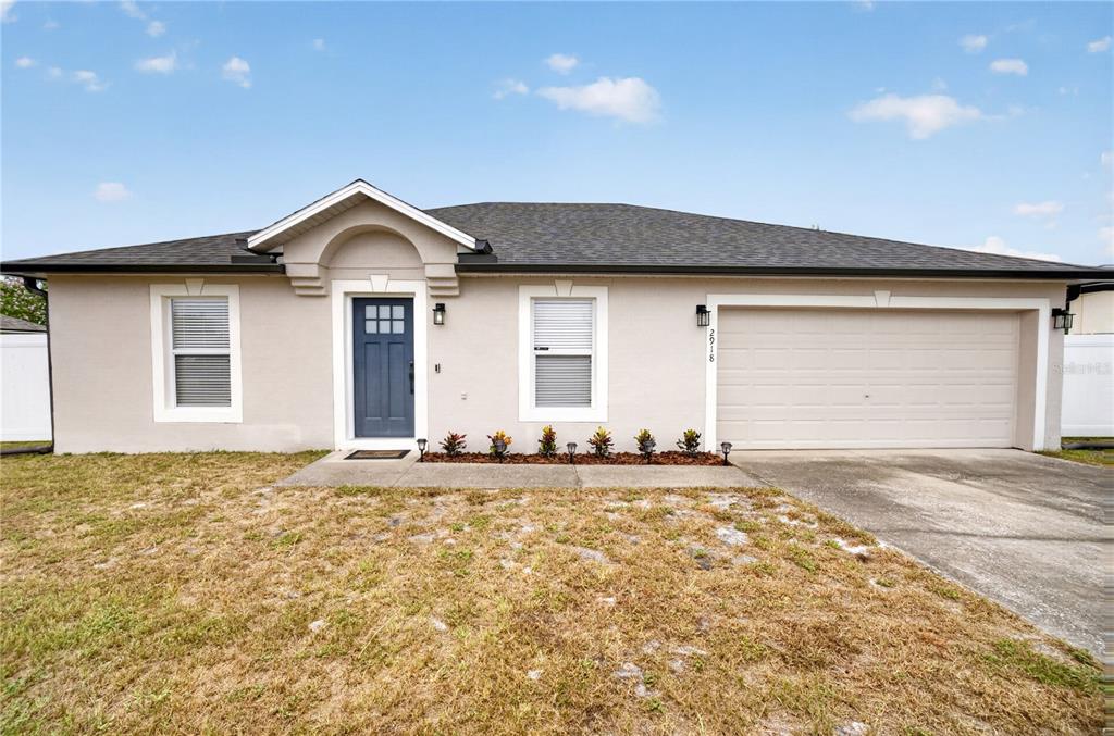 A single-story house with a beige stucco exterior, a blue front door, and a garage — 2918 CHALMER STREET, DELTONA, FL