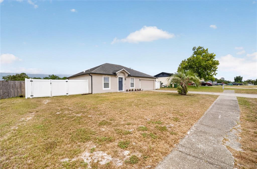 A single-story house with a beige exterior, a dark roof, and a white vinyl fence — 2918 CHALMER STREET, DELTONA, FL