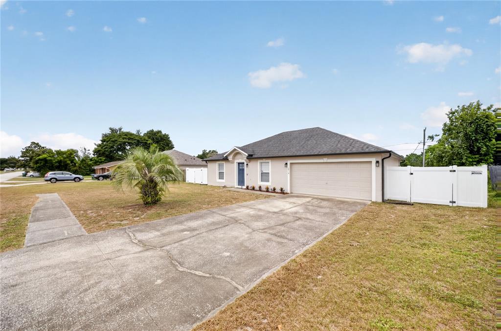A single-story house with a beige exterior, a two-car garage, and a concrete driveway — 2918 CHALMER STREET, DELTONA, FL