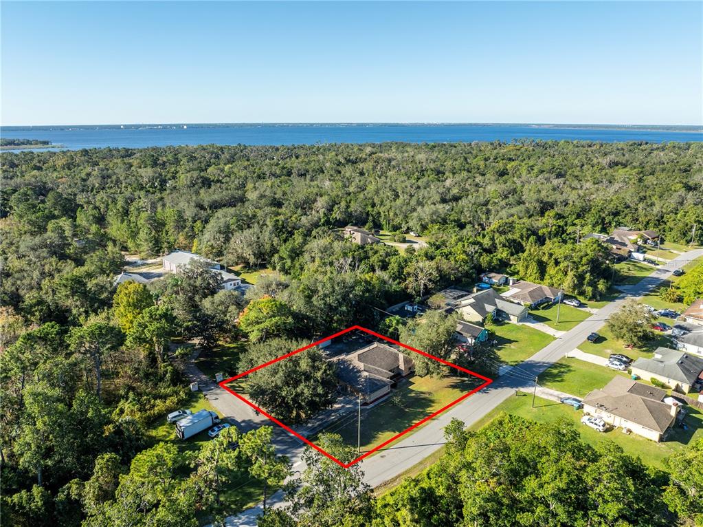 An aerial view shows a house with a red outline situated in a wooded neighborhood — 1191 S BRICKELL DRIVE, DELTONA, FL